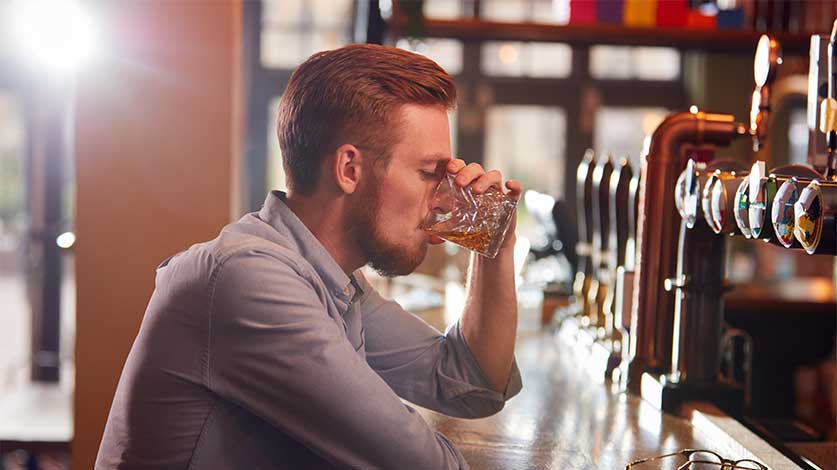 middle aged man drinking alone at a bar - Drinking Alone & The Risk Of Future Alcohol Problems