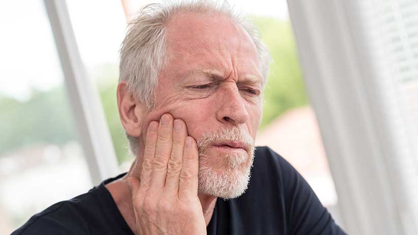 man holding his jaw in pain - What Is Coke Jaw?