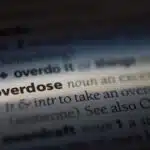 A dictionary page with a highlight over the word Overdose, the rest of the page is in shadow - Can You Overdose On Ritalin Symptoms & Treatment