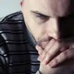 A depressed man with his hands clasped looking downward - Does Dexedrine Help With Or Worsen Depression