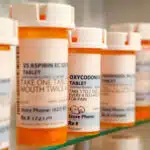 A row of pill bottles sit on a glass - Does vyvanse expire?