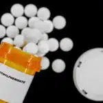 Pills spill out of an orange prescription bottle with a label that reads "Methylphenidate" - Is Ritalin (Methylphenidate) An Amphetamine?