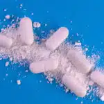 7 pills lie on a pile of white powder- Snorting Dexedrine Effects & Dangers Of Insufflation
