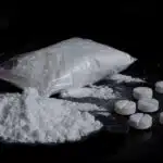 7 white circular pills lie next to a pile and a bag of white powder - Snorting Ritalin (Methylphenidate) Effects & Dangers Of Insufflation