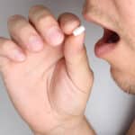 A close up of a man taking a white pill - What Do Xanax Pills Taste Like