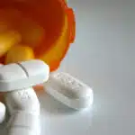 White pills spill out of an orange prescription bottle - Why Ritalin Is A Controlled Substance