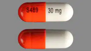 An orange and white Vyvanse capsule with S489 and 30 mg printed on it