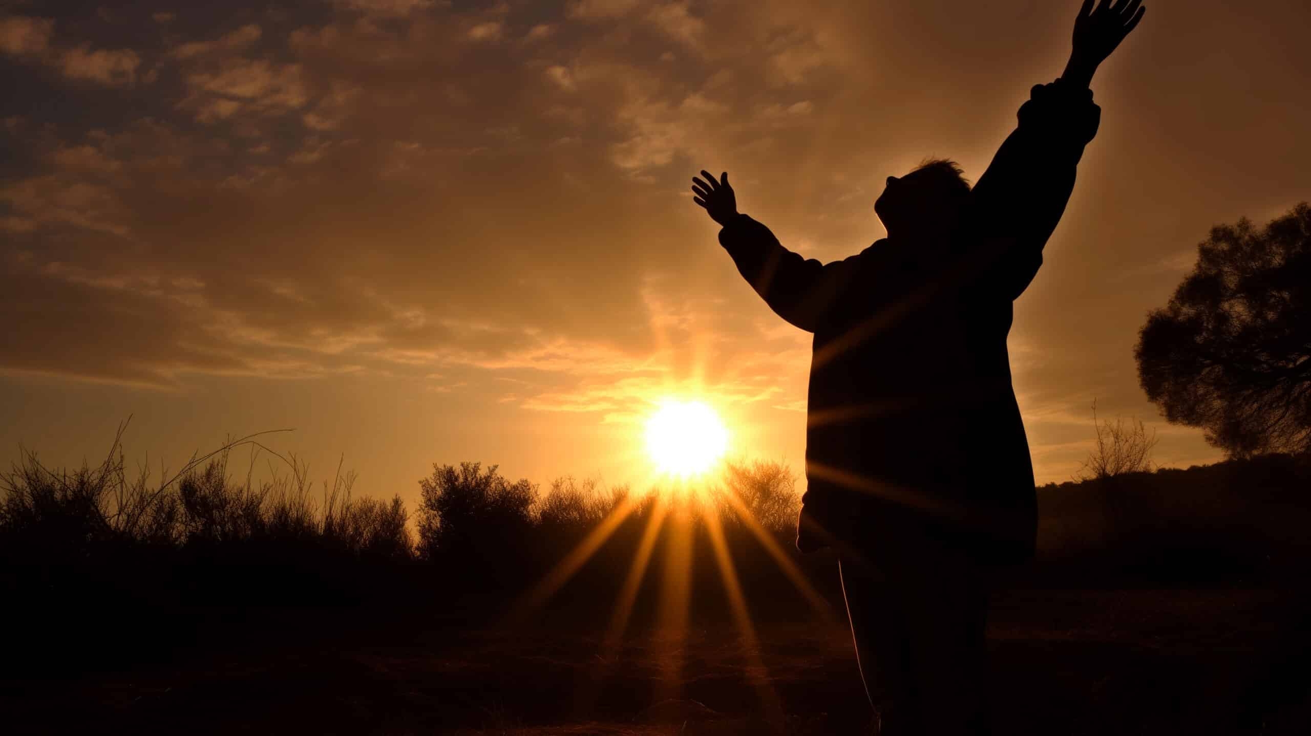 A silhouette of a man standing happily in front of a sunset - 10 Tips For Maintaining Long-Term Addiction Recovery