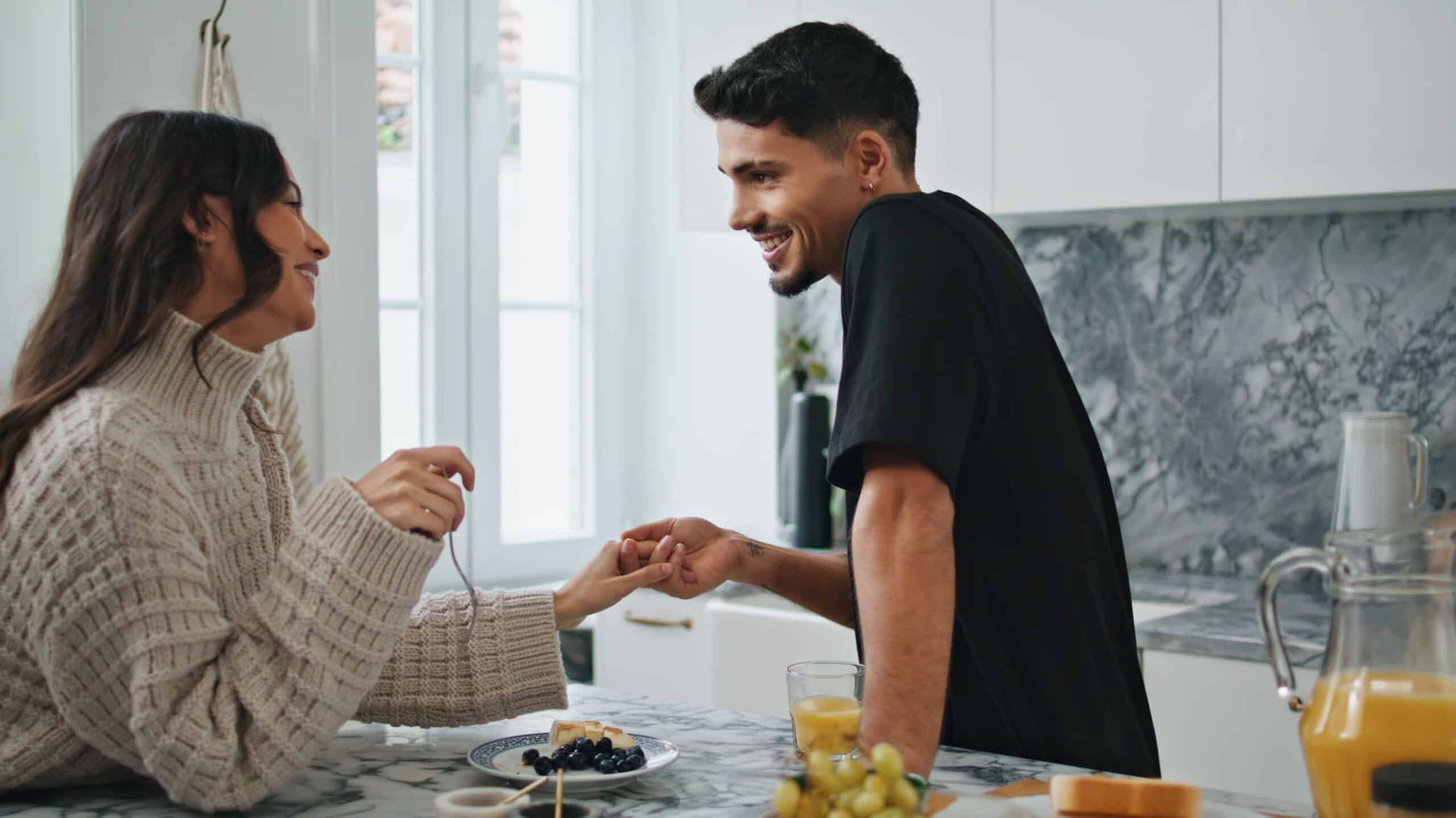 A man and woman hold hands across a countertop - How To Tell Your Spouse You're Getting Help For Substance Use