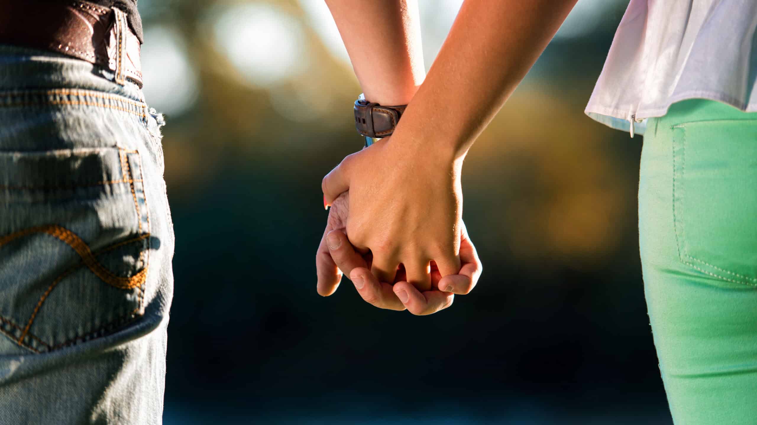 A couple holds hands while walking - Dating In Early Recovery Risks & Benefits