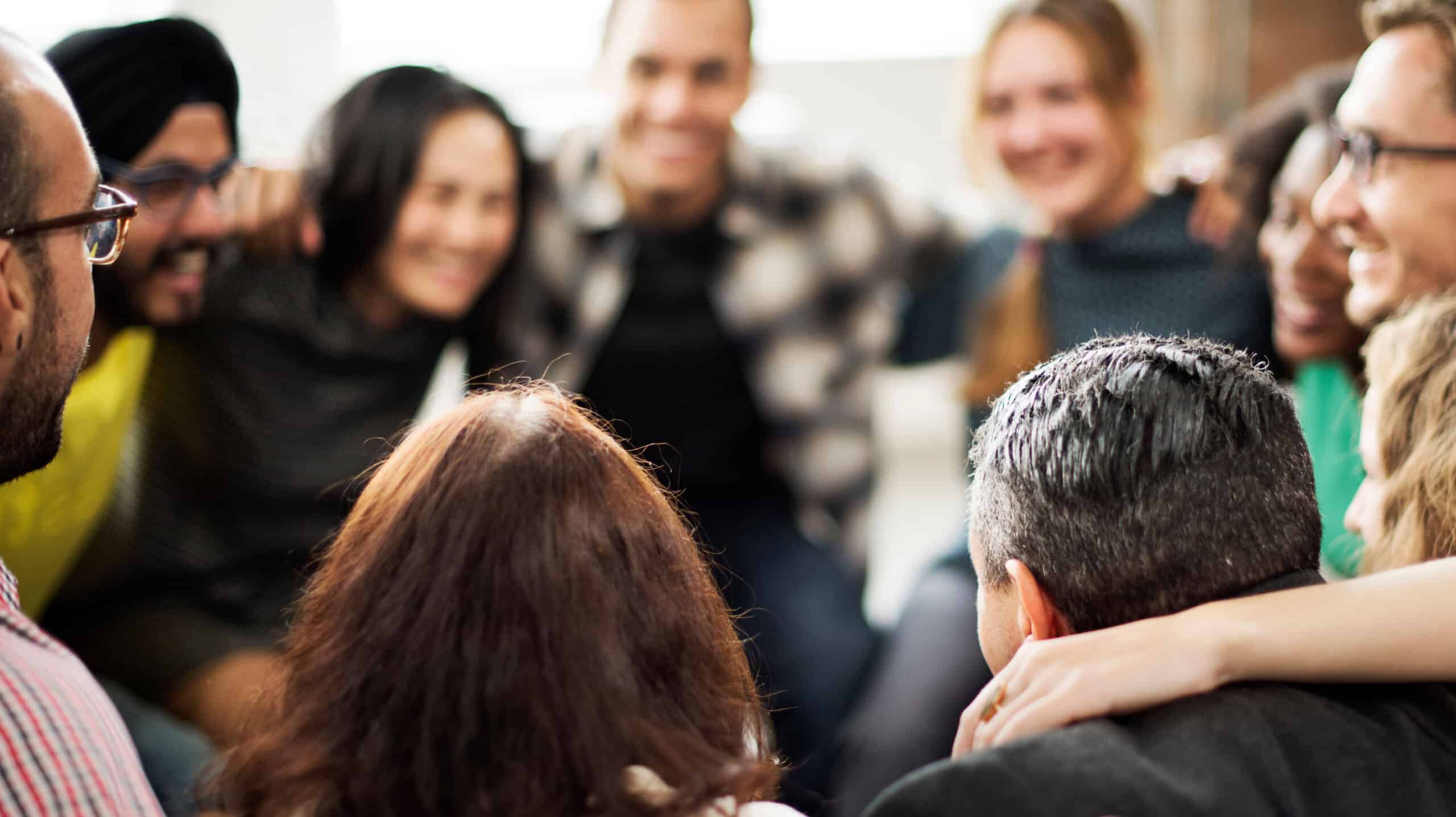 People stand in a circle with their arms around each other's shoulders - How Alumni Programs Can Help You Stay Sober